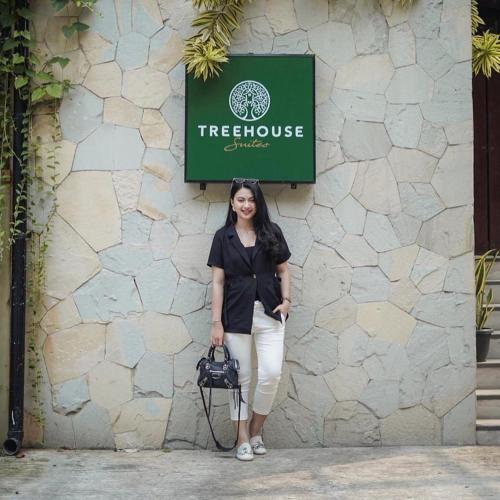 a woman is standing in front of a wall at Treehouse Suites - Boutique Serviced Apartment in Jakarta