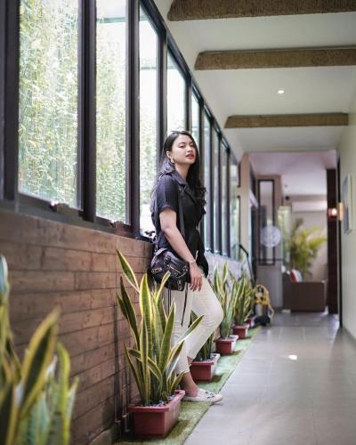 a woman is leaning against a wall with plants at Treehouse Suites - Boutique Serviced Apartment in Jakarta