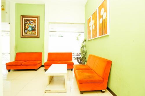 dos sillas naranjas y una mesa en una sala de espera en Ardhya Guesthouse Syariah by ecommerceloka en Sidoarjo
