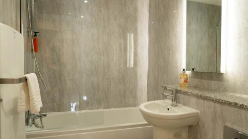 a bathroom with a sink and a toilet and a tub at Hill Of Oaks in Windermere