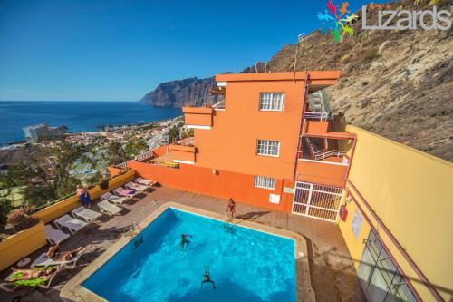 a building with a swimming pool next to the ocean at 7Lizards - Ocean View Apartments in Puerto de Santiago