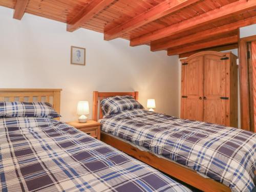 two twin beds in a room with wooden ceilings at Viola Cottage in Fraserburgh