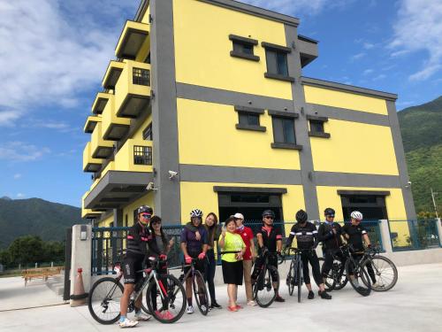 a group of people standing in front of a yellow building at 太魯閣惠宇民宿 in Xincheng