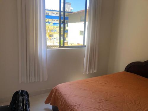 1 dormitorio con cama y ventana en Apartamento na praia, quadra do mar, en Itapema