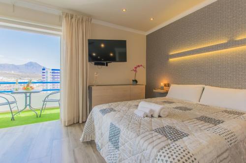 Schlafzimmer mit einem Bett, einem TV und einem Balkon in der Unterkunft Cozy Studio in Paraiso Del Sur - TENESOL RENTALS in Adeje