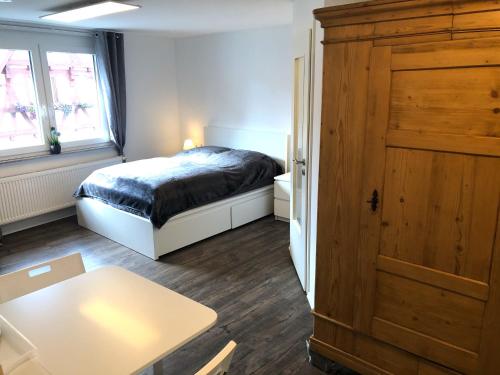 a bedroom with a bed and a table and a door at Lisas Gästehaus in Neckartenzlingen