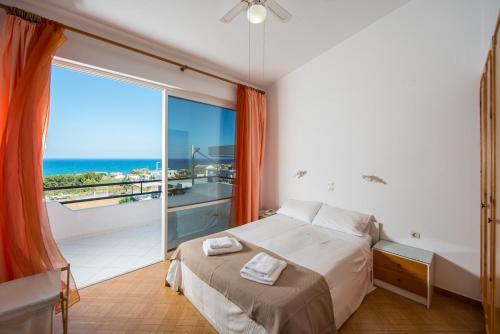 sypialnia z łóżkiem i balkonem z widokiem na ocean w obiekcie Rouladina Apartments w Stalós