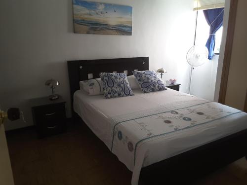 1 dormitorio con 1 cama con almohadas azules y blancas en Apartment Riberas, en Cali
