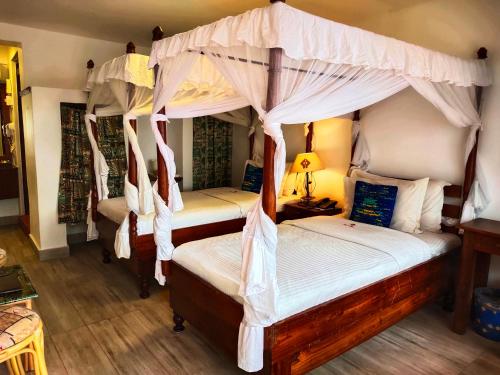 a bedroom with four canopy beds and a lamp at Hotel Tilapia in Mwanza