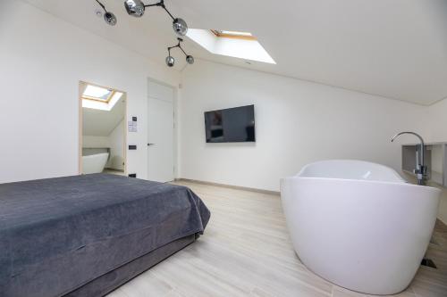 a white bedroom with a bed and a white chair at M50 Apartments in Palanga