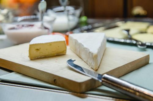 a cutting board with cheese and a knife on it at Hotel Müller in Genthin