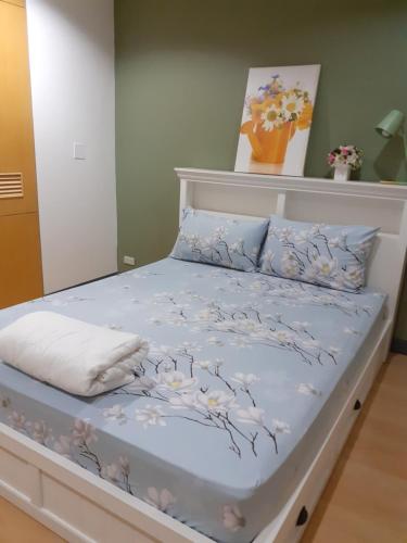 a bed with a blue comforter with flowers on it at BaanSu Hostel in Bangkok