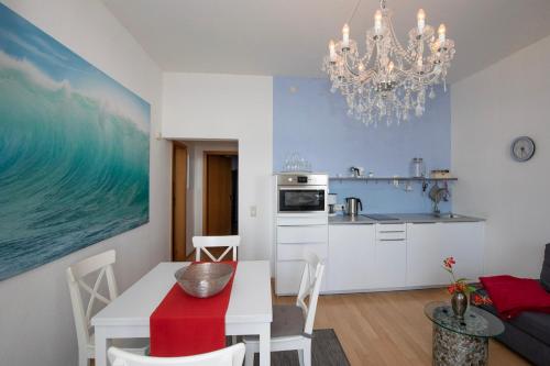 a kitchen and dining room with a table and a chandelier at Fürstenhof - Ferienwohnung 106 in Sassnitz