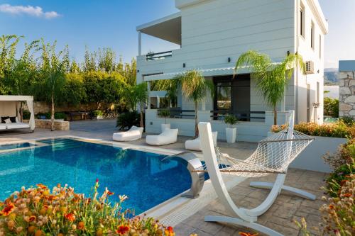 a villa with a swimming pool with a hammock and a house at Villa Green Diamond - Private Heated Pool in Platanes