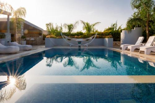 a swimming pool with white chairs and a swimming pool at Villa Green Diamond - Private Heated Pool in Platanes