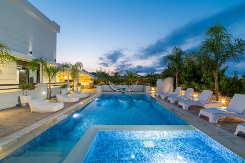 a swimming pool with lounge chairs and a villa at Villa Green Diamond - Private Heated Pool in Platanes