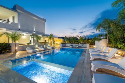an outdoor swimming pool with lounge chairs and a villa at Villa Green Diamond - Private Heated Pool in Platanes