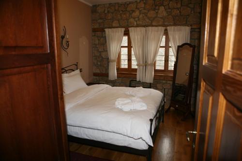 a bedroom with a bed with white sheets and two windows at Roes Suites in Kato Loutraki