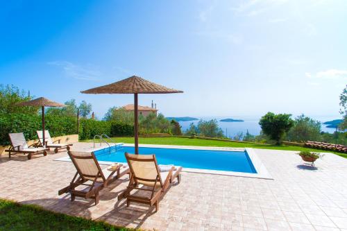 a swimming pool with chairs and umbrellas next to at Villa Angela in Skiathos