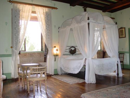 Paço de S.Cipriano في غيمارايش: غرفة نوم بسرير مظلة مع طاولة وكراسي