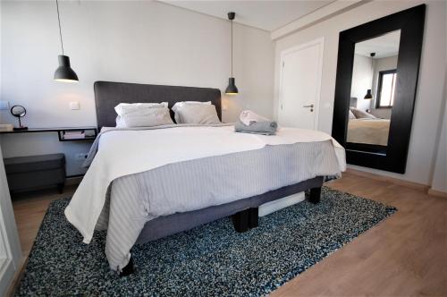 1 dormitorio con 1 cama grande y espejo grande en Villa Valhalla - Free Heated Swimming Pool - by bedzy Vilamoura LUX en Vilamoura
