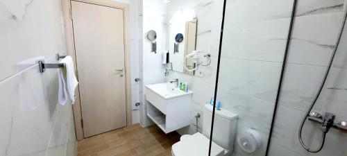 a bathroom with a toilet, sink, and shower stall at Hotel DOA in Skopje