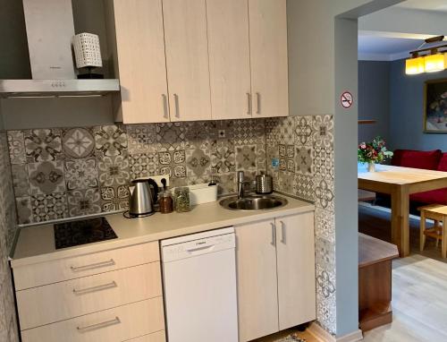 a kitchen with white cabinets and a sink at Hostel Kastaņas in Lielvārde