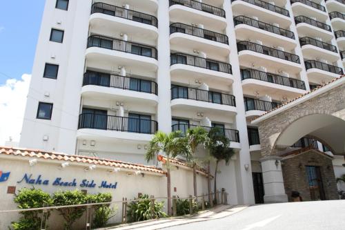 un gran edificio blanco con un cartel delante en Naha Beach Side Hotel, en Naha