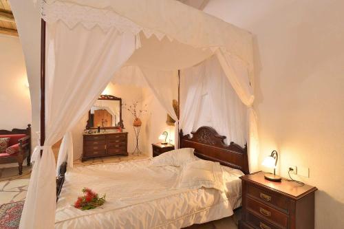 a bedroom with a canopy bed with a dresser and a mirror at Villa Kamares Private pool in Kondomari