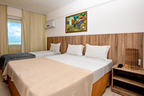 um quarto de hotel com duas camas e um piano em Brisa do Mar Beach Hotel em Natal