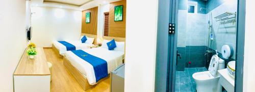 Duas camas num quarto com um chuveiro e uma casa de banho em Khải Hoàn Hotel em Bến Cát