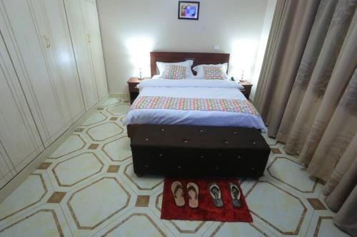 a bedroom with a bed and two pairs of shoes at Precious Villas Lubowa in Kampala