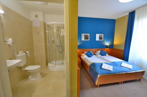 uma casa de banho com uma cama, um chuveiro e um WC. em Hotel Platan em Székesfehérvár