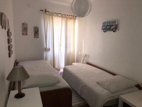 due letti in una piccola stanza con una finestra di Cliff House next to beach a Ericeira