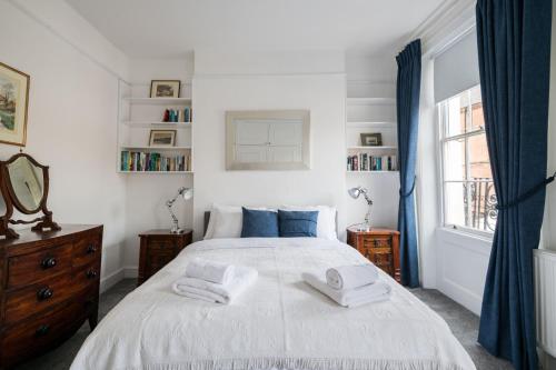 a bedroom with a white bed with towels on it at Stylish Sloane Square Home Close to Victoria by UndertheDoormat in London