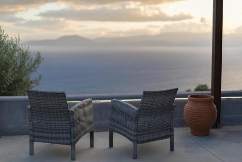two chairs sitting on a balcony looking at the ocean at Gems of Pinakates in Pinakátai