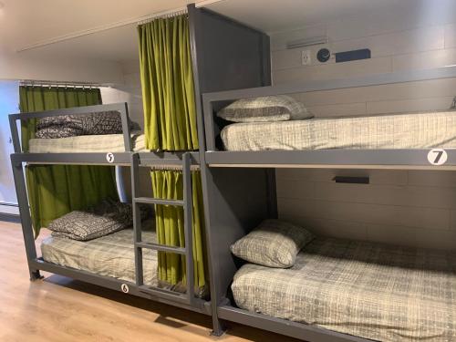 four bunk beds in a room with green curtains at Jasper Downtown Hostel in Jasper