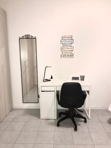 a desk with a black chair and a mirror at Apartment Forum III in Assago