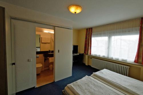 a hotel room with two beds and a bathroom at Hotel Wiedenhof in Hilden