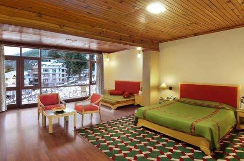 a bedroom with a large bed and a large window at Shingar Regency in Manāli