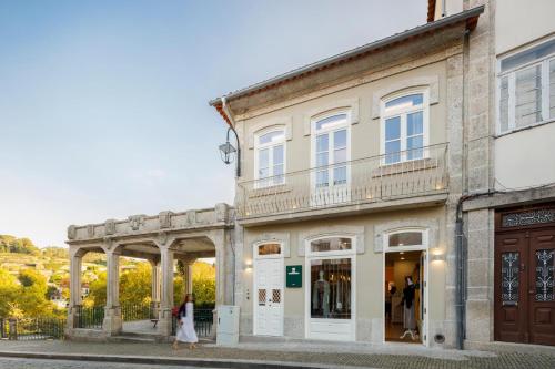 a woman walking in front of a building at Casa do Fontanário Stay in Amarante