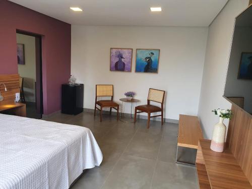 a bedroom with a bed and two chairs and a table at Capão do Cerrado Pousada e Spa in Itabirito