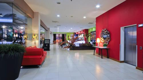 a lobby with a red couch and a red wall at Holiday Inn Irapuato by IHG in Irapuato