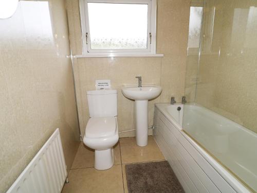 a bathroom with a toilet and a sink and a bath tub at Hazel Cottage in Portrush