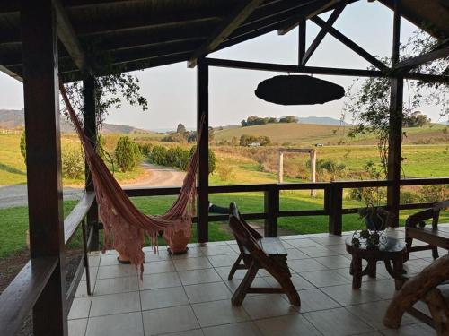 a porch with a hammock and a view of a field at Casa de campo Recanto das Borboletas in Bom Retiro