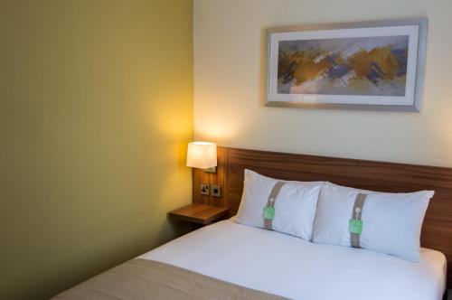 a bedroom with a bed and a picture on the wall at Holiday Inn Leeds Garforth by IHG in Garforth