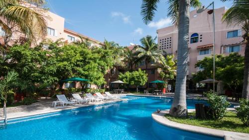 a swimming pool in a resort with chairs and palm trees at Holiday Inn Ciudad Del Carmen by IHG in Ciudad del Carmen