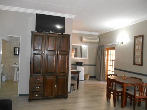 a living room with a television on top of a wooden cabinet at Oakwood Lodge in Bloemfontein