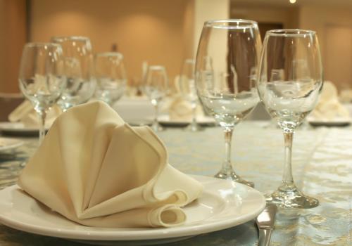 a white plate with a napkin on a table with wine glasses at Holiday Inn Leon-Convention Center by IHG in León