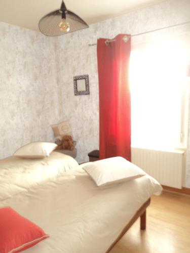 a bedroom with two beds and a red curtain at maison aux volets bleus in Quévert